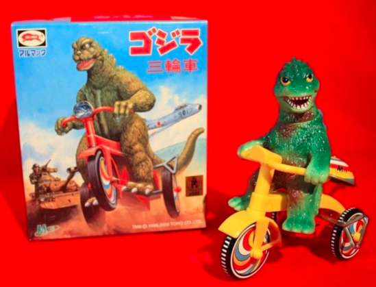 Juguete japonés de Godzilla montado en bicicleta o a saber porque el lagarto es feo pero tela