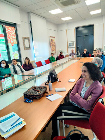 Se ve una mesa larga con gente del grupo Infobisoc escuchando a una persona que no se ve en la foto