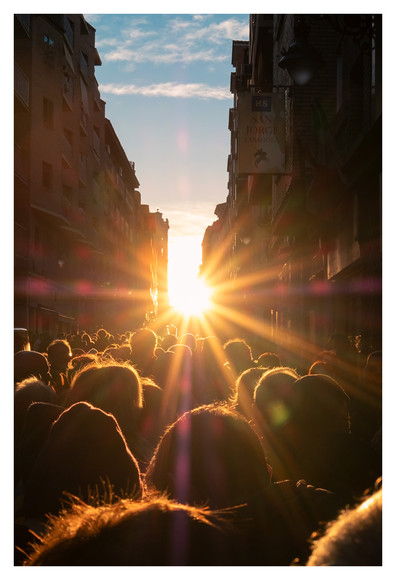 Foto del sol de frente, alineado en el centro de una larga calle, con el cielo despejado y muchas cabezas de personas que estaban viendo el acontecimiento.