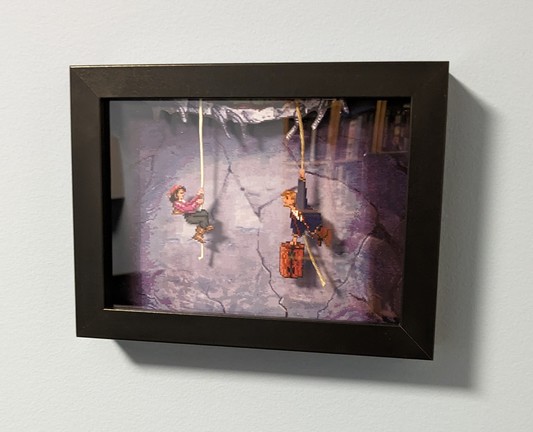 Cuadro con relieve en el que aparece la escena inicial de Monkey island 2, en la que Elaine y Guybrush colgando en un agujero