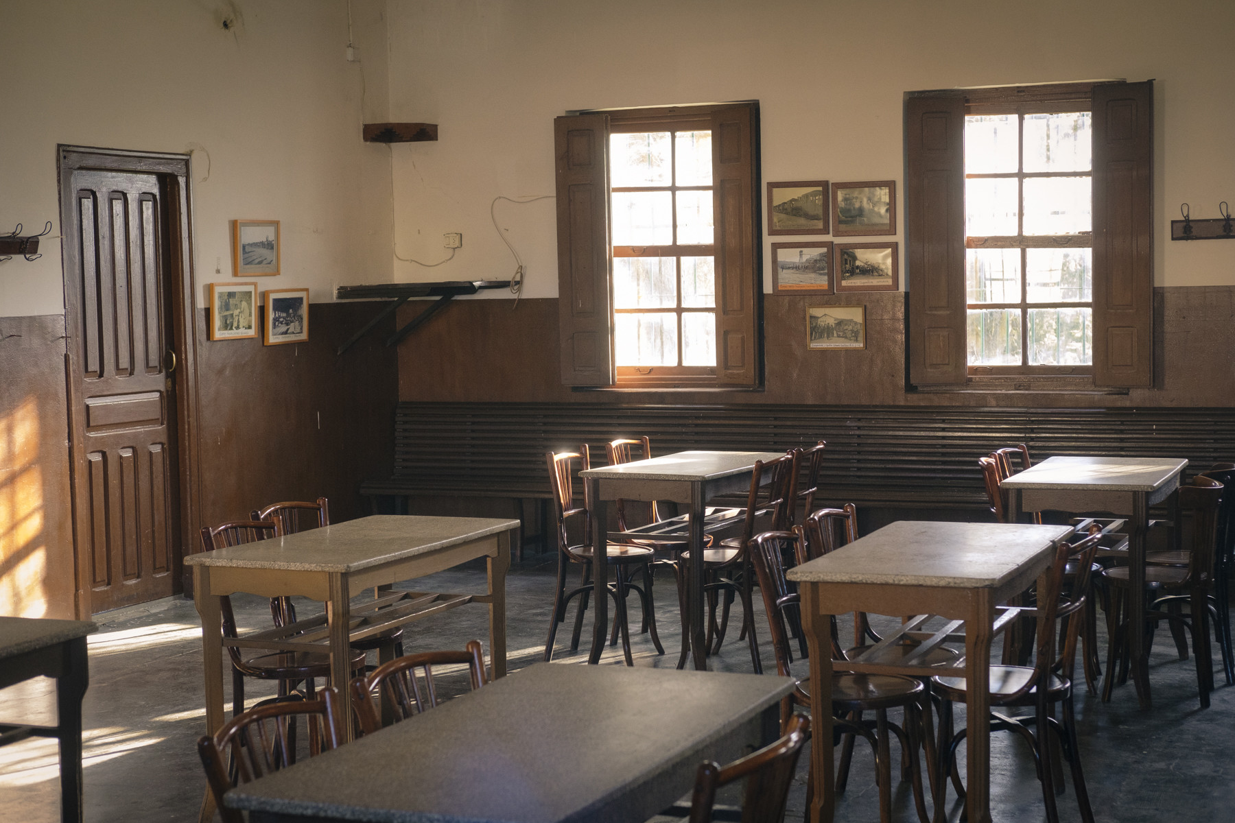 El interior del local La Cultural, en Tormos. La luz del atardecer ilumina las mesas, sillas, puertas y ventanas que estarán ahí desde mediados del siglo pasado.