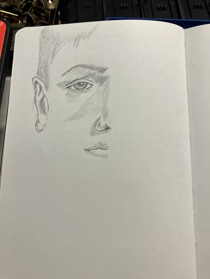 Boceto hecho a lápiz en una libreta de medio rostro de un hombre joven.