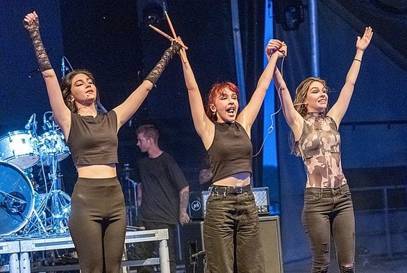 Las tres hermanas saludando al público con los brazos en alto.
