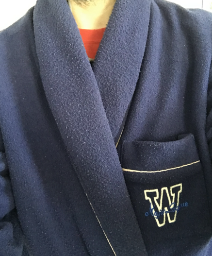 Fotoyo en la que no se me ve la cara, solamente parte del torso con una bata azul aburrida y un poco raída ya. En un bolsillo en el pecho hay una W grandota.