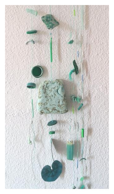 Móvil hecho con plásticos recogidos d la playa d tonos verdes. Palos d chupete, tapas, hojas plásticas, un auricular, etc. cuelgan atados a hebras d cuerdas d pesca. 