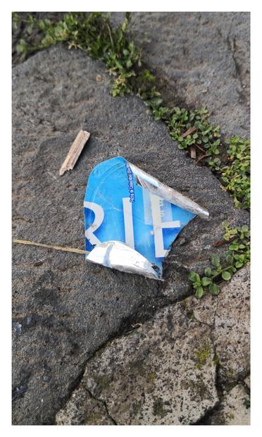 Tapa d yogurt griego tirada en la calle. Se leen las letrs R, I, E: RIE