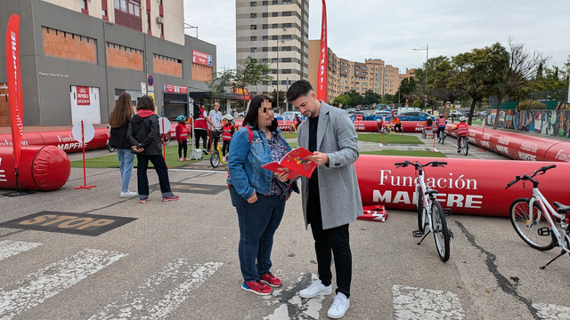 El excelentísimo concejal de Movilidad Sostenible, Transición Ecológica y otras movidas, Miguel Fuentes, que además da la casualidad de que es mi señor jefe, sujetando una revista mientras la observa fijamente. Ya os digo yo que no la estaba leyendo.

Al fondo, un montonazo de niños y niñas recorren el circuito que montó la Fundación Mapfre en la misma calle.