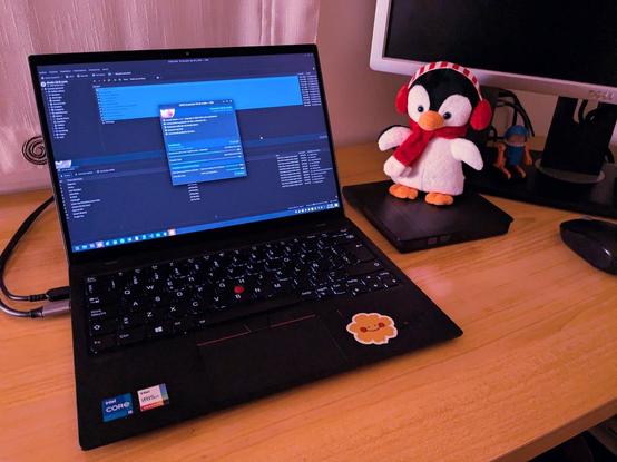 Un portátil grabando un CD de audio. Tiene conectada una grabadora externa USB sobre la que hay un pequeño peluche de un pingüino con bufanda y orejeras, porque la foto la hice en navidad.