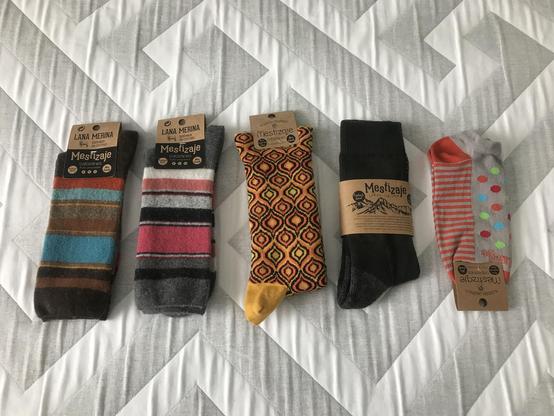 Surtido de calcetines de la marca Mestizaje sobre una colcha de cama. De vivos colores. 4 pares de media canay un par de verano.