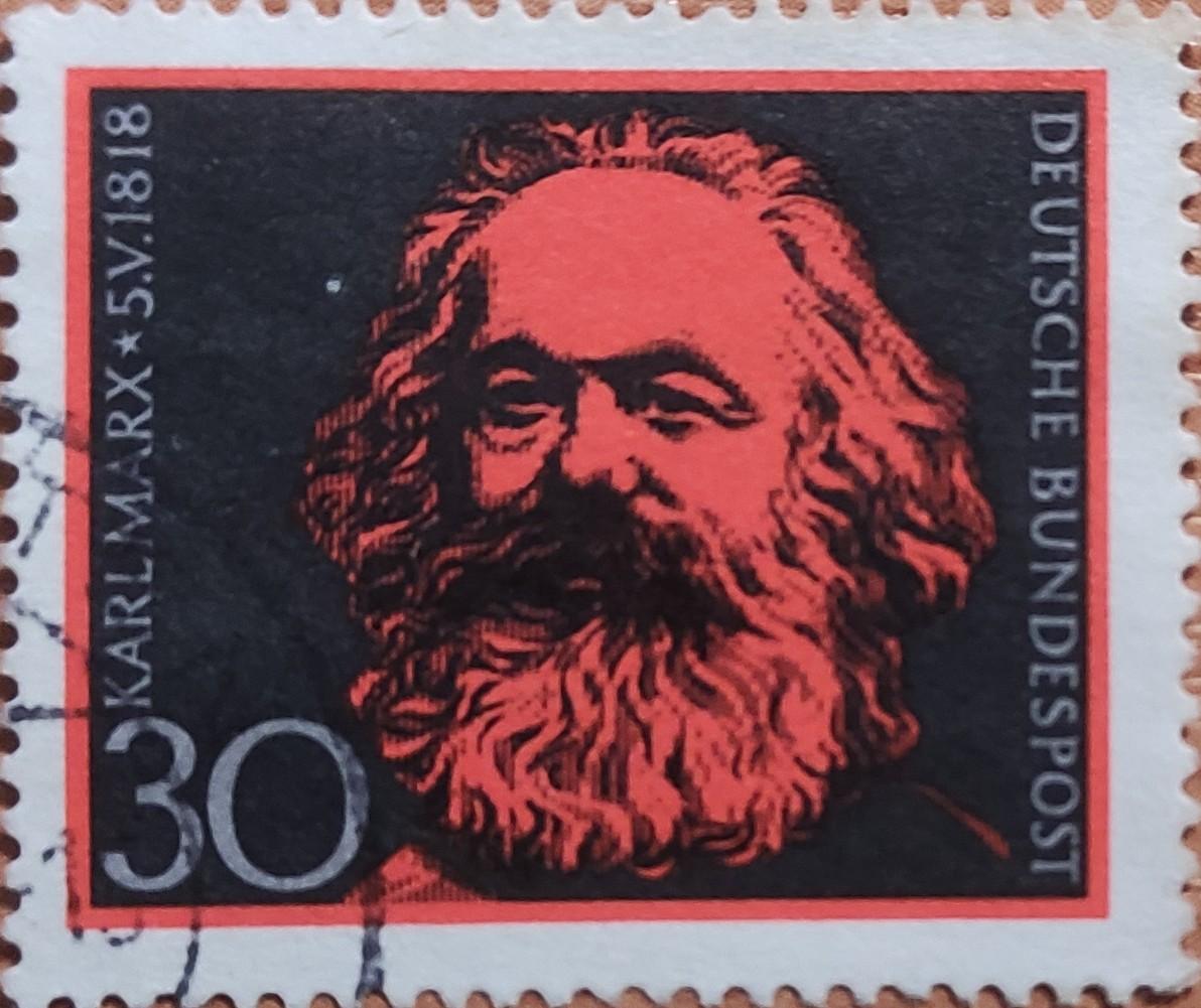 Sello en color rojizo con la cara de Karl Marx. El fondo en negro. Valor postal de 30 Pfennig Alemanes